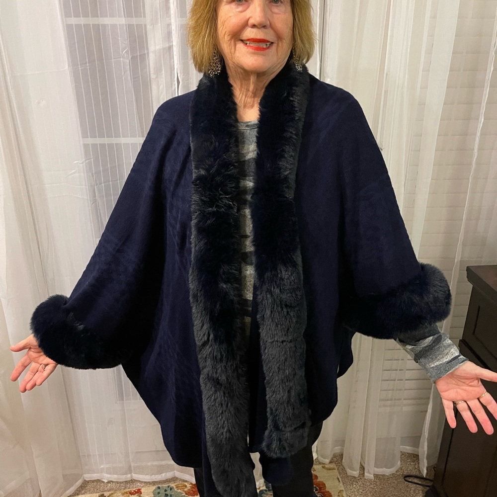 Navy pancho with faux fur trim. Knitted sweater body with subtle stripe detail.